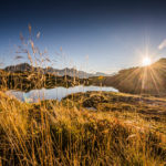 Sonnenuntergang am spiegelglatten Bergsee in Obertauern mit bergiger Silhouette im Hintergrund